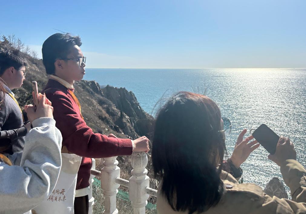 台湾学生简星宇（右二）与同学在大连旅顺老铁山观景台俯瞰黄渤海分界线（4月24日摄）。新华社记者 李妍 摄