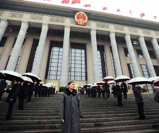 人民大会堂前,工作人员打着伞迎接代表。