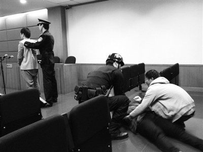 法警勸被告人母親站起。昨日，被告人因涉嫌搶劫罪受審，檢方建議判處死刑。被告人母親情緒激動哭倒在地。新京報記者 張媛 攝