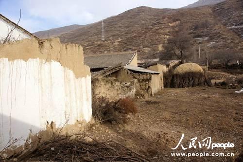甘肃漳县大草滩乡新联村,“遮羞墙”内农户破败的房屋和院墙与新墙形成鲜明对比(人民网记者 高翔 张鹏 隋欣 摄)