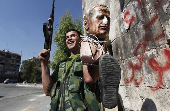 叙利亚内战中,叙利亚自由军的一名士兵举着已故前总统阿萨德的塑像.