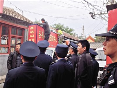 昨日下午，东城区工商、城管、公安等部门，对雍和宫附近的预测中心进行清理整顿，站在车顶的两名工人正拆除一家“预测中心”的招牌。因雍和宫、白云观等文化景点外聚集大量算命先生，被媒体称为“算命一条街”。本版摄影/新京报记者 李宁 摄
