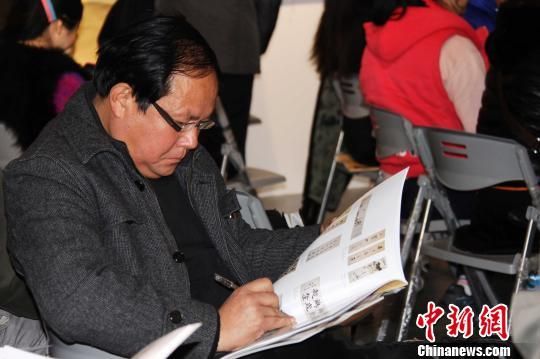 由山东省资源总公司主办的首届“慧眼识宝”书画拍卖会11月30日在济南阳光100文化艺术馆举行,图为竞拍者阅读拍卖产品图录,挑选心仪的作品。 黄品璇 摄