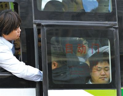 售票员用手将门口的乘客往里推，以便车门能顺利关上。
