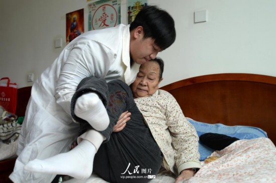 4月28日,25岁的熊海波将85岁的曾庆福老太太抱在床上。