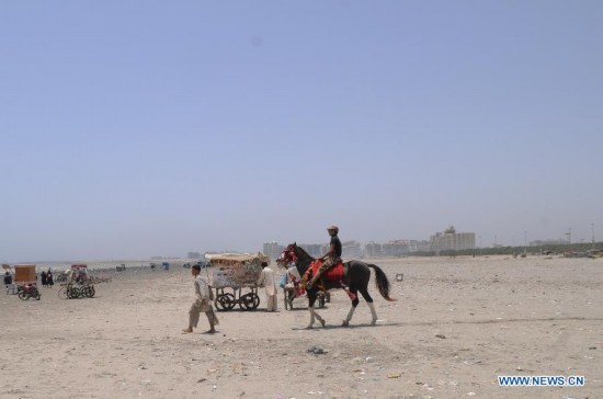 A tourist rides on a horse at a beach in southern Pakistani port city of Karachi on June 6, 2014. (Xinhua/Masroor) 