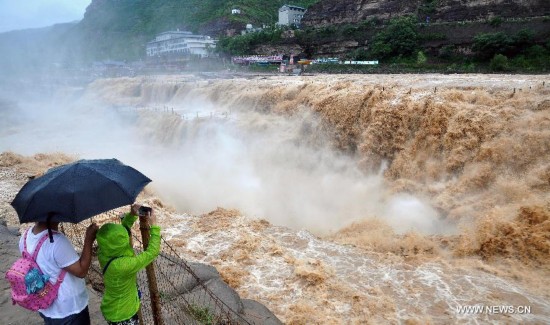 Tourists take photos of the Hukou Waterfall of the Yellow River, north China's Shanxi Province, July 9, 2014. (Xinhua/Fan Minda) 