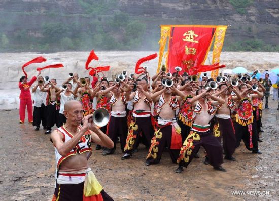 Performers play suona horns near the Hukou Waterfall of the Yellow River, north China's Shanxi Province, July 9, 2014. (Xinhua/Fan Minda) 