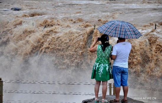 Tourists take photos of the Hukou Waterfall of the Yellow River, north China's Shanxi Province, July 9, 2014. (Xinhua/Fan Minda) 