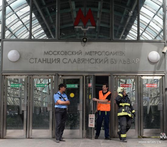 Rescuers and repair personnel stand outside the Slavyanski Bulvar subway station in Moscow, capital of Russia, on July 15, 2014. At least 16 people have been confirmed dead after a metro train derailed in Moscow during the morning rush hour on Tuesday, Russian Emergency Situations Minister Vladimir Puchkov said.