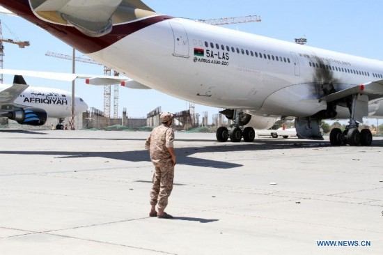 A militia stands near a damaged plane in Tripoli International Airport, in Libya, on July 16, 2014. 