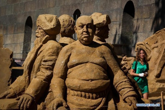 A visitor walks past sand sculptures displayed during the international festival of sand sculptures in St.Petersburg, Russia, on July 17, 2014.