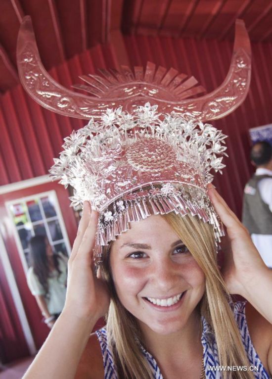 A woman tries to wear a silver head ornament during the 'Colorful Guizhou Exhibition' in the Town of Niagara-on-the-Lake, Ontario, Canada, July 22, 2014. 