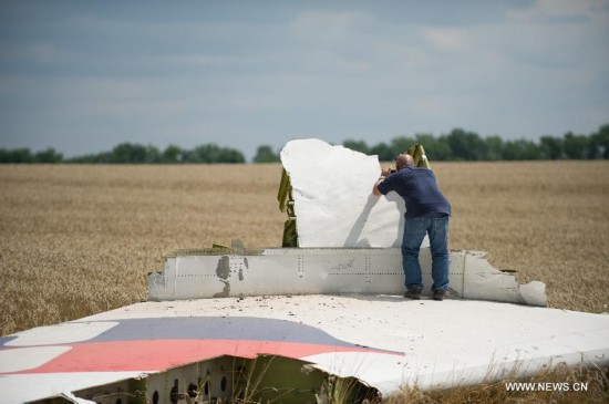 An expert from Malaysian investgation team takes photos of debris of airplane at the crash site of flight MH17 of Malaysia Airlines in Ukraine's Donetsk region, on July 22, 2014. 