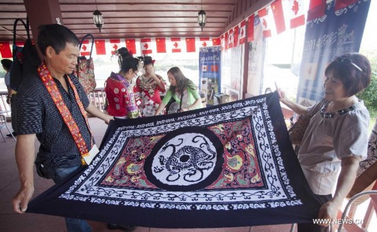 Visitors look through a piece of batik cloth during the 'Colorful Guizhou Exhibition' in the Town of Niagara-on-the-Lake, Ontario, Canada, July 22, 2014.