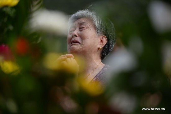 A resident mourns for her relatives died in the 1976 Tangshan earthquake in front of the memorial wall in Tangshan, north China's Hebei Province, July 28, 2014