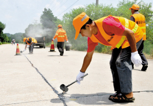 养护工人对道路进行沥青灌缝.