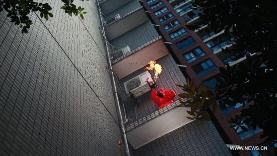 Firefighter Chen Jihang, a firefighter serving in Tongjiaqiao Fire Squadron, climbs to a residential building to burn a honeycomb in Chongqing, southwest China, Aug. 25, 2013. 