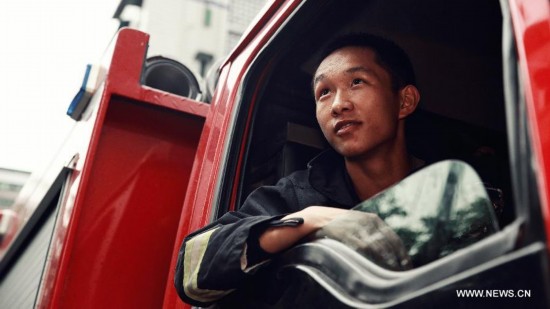 Firefighter Chen Jihang, a firefighter serving in Tongjiaqiao Fire Squadron, sits in a fire engine in Chongqing, southwest China, July 24, 2014. 