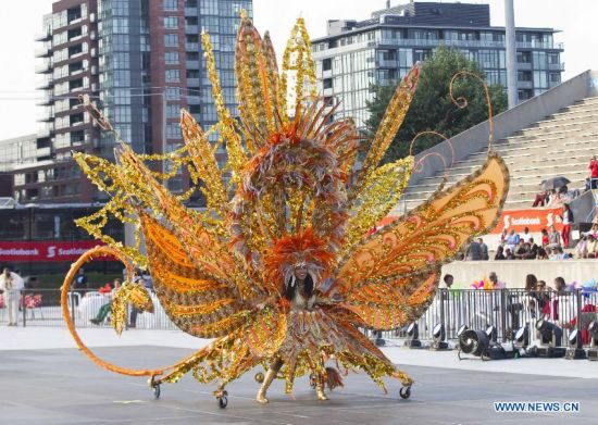 A dressed up competitor perfroms with her float during the King and Queen Competition and Show of the 47th Toronto Caribbean Carnival in Toronto, Canada, July 31, 2014