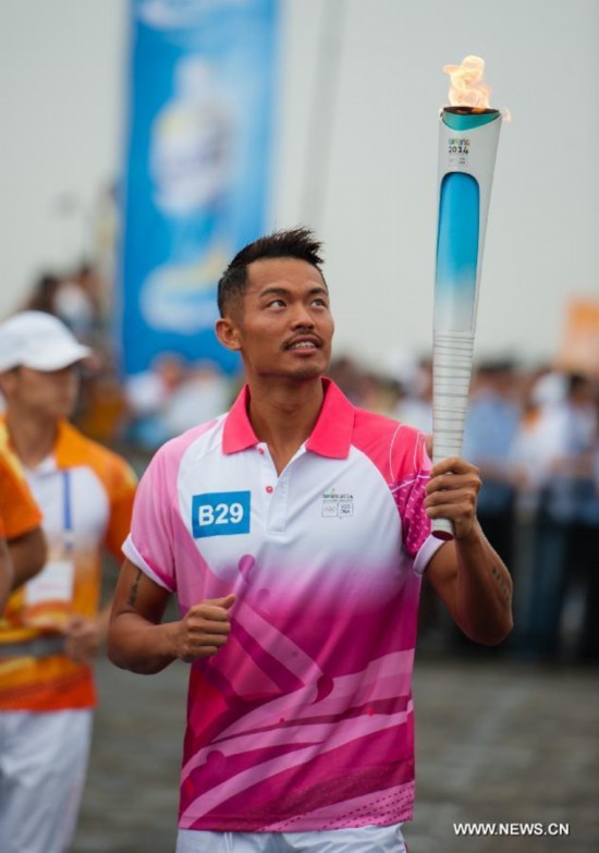 Chinese famous badminton player Lin Dan runs with the Olympic torch on the city wall during the Olympic Torch Relay for the Nanjing Youth Olympic Games in Nanjing