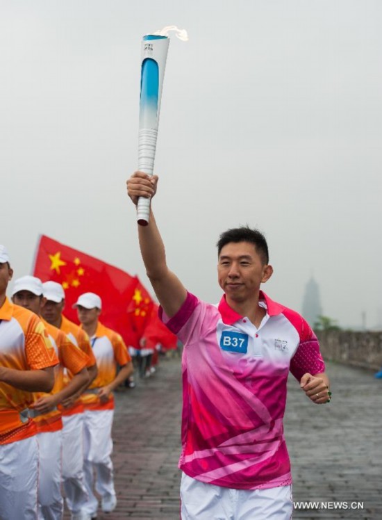 Torch bearer Lin Weixiong runs with the Olympic torch on the city wall during the Olympic Torch Relay for the Nanjing Youth Olympic Games in Nanjing