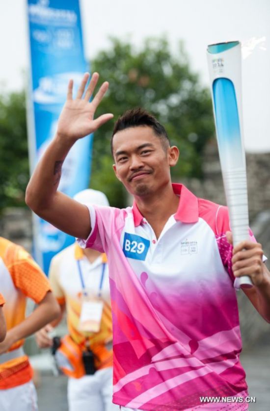 Chinese famous badminton player Lin Dan runs with the Olympic torch on the city wall during the Olympic Torch Relay for the Nanjing Youth Olympic Games in Nanjing