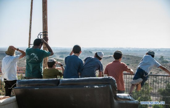 Jewish teenagers look at Gaza Strip from Sderot, south Israel bordering the Gaza Strip, on Aug. 20, 2014. Israel will step up the offensive in the Gaza Strip until rocket firing from there into Israel stops, Prime Minister Benjamin Netanyahu said Wednesday, in response to renewed Gaza rocket attacks against central and southern Israel earlier in the day. (Xinhua/Li Rui) 