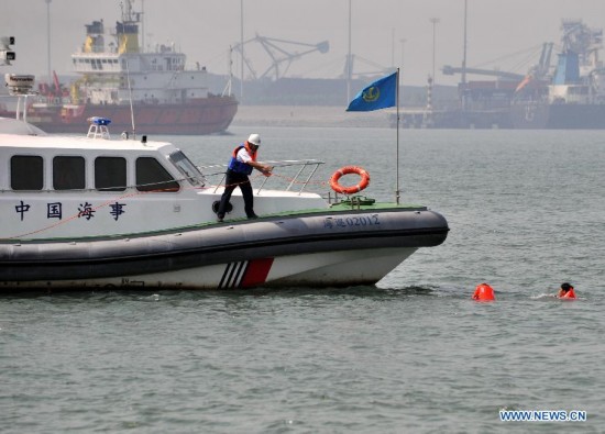 A rescuer tries to help the people in the water during a marine rescue drill on the sea water off Tianjin, north China, Aug. 26, 2014. Some 200 people and 16 vessels were involved in the drill here on Tuesday.