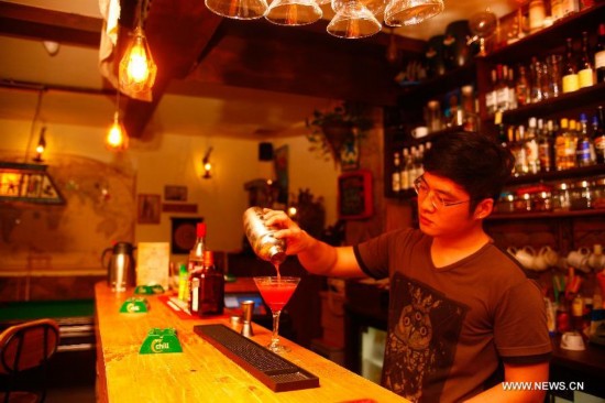 A bartender works at the Chilanqiao cultural block on Shuguangbei Street in Heifei, capital of east China's Anhui Province, August 27, 2014. The cultural block, used to be a hub for junk dealers, has become a favorite destination for artists and culture lovers with its bookstores, galleries, bars and coffee houses and hostels after its reconstruction starting in 2012. (Xinhua/Zhu Weixi)