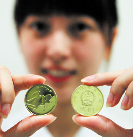 银行工作人员展示去年9月央行发行的5元“和”字币。 新华社发