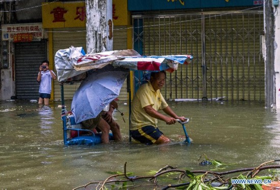 A man rides on flooded road in typhoon-hit Haikou, capital of south China's Hainan Province, Sept. 16, 2014. Seawater flew backward into the city as typhoon Kalmaegi landed in the island province on Tuesday morning. (Xinhua/Jiang Jurong)