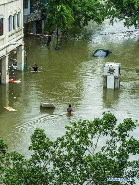 People walk on flooded road in typhoon-hit Haikou, capital of south China's Hainan Province, Sept. 16, 2014. Seawater flew backward into the city as typhoon Kalmaegi landed in the island province on Tuesday morning. (Xinhua/Jiang Jurong)