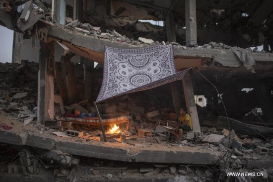 Palestinian men light a fire to illuminate their neighborhood, which was destroyed during the 50-day conflict between Israel and Hamas, in the Shejaiya neighborhood of Gaza City, on Sept 24, 2014. 