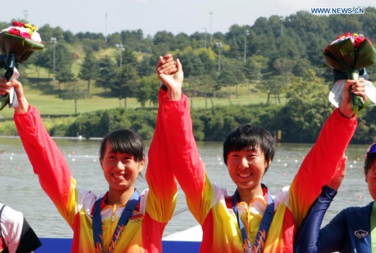 Chen Le (L) and Zhang Huan of China pose during the awarding ceremony of the lightweight women's doubles sculls of rowing at the 17th Asian Games in Chungju, South Korea, Sept. 25, 2014. China won the gold medal.