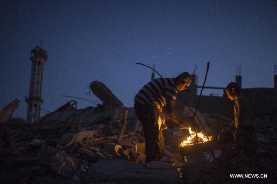 Palestinian men light a fire to illuminate their neighborhood, which was destroyed during the 50-day conflict between Israel and Hamas, in the Shejaiya neighborhood of Gaza City, on Sept 24, 2014. 