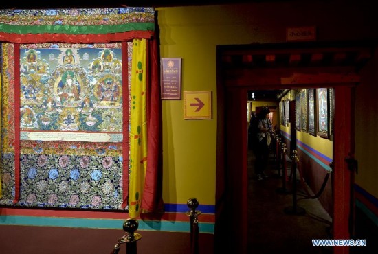 Visitors view tangka, a style of Tibetan art that involves painting on embroidery, during a tangka art festival in Lhasa, capital of southwest China's Tibet Autonomous Region, Sept. 25, 2014