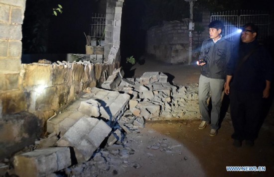 Villagers check the damaged house at Mangla Village of Yongping Township at Jinggu County of Pu'er City, southwest China's Yunnan Province, Oct. 8, 2014.