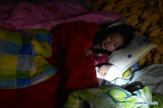 Villager Dao Yanling sleeps with her three-month-old son in the open air at Mangla Village of Yongping Township at Jinggu County of Pu'er City, southwest China's Yunnan Province, Oct. 8, 2014.