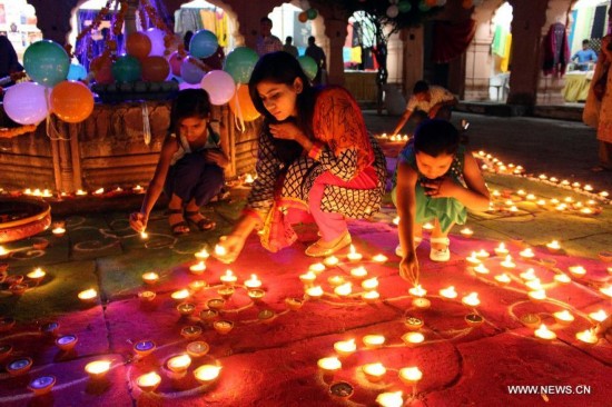 People light earthen lamps during the celebration of Diwali ahead of the festival at Gauhar Mahal in Bhopal, India, Oct. 18, 2014. 