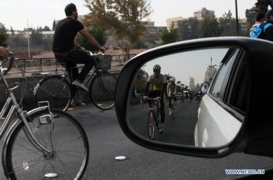 Locals ride bicycles on a street in Damascus, Syria, Nov. 21, 2014, as part of a campaign aimed to raise awareness among Syrians on energy-saving and environmental protection.