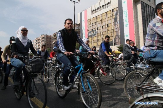 Locals ride bicycles on a street in Damascus, Syria, Nov. 21, 2014, as part of a campaign aimed to raise awareness among Syrians on energy-saving and environmental protection. 