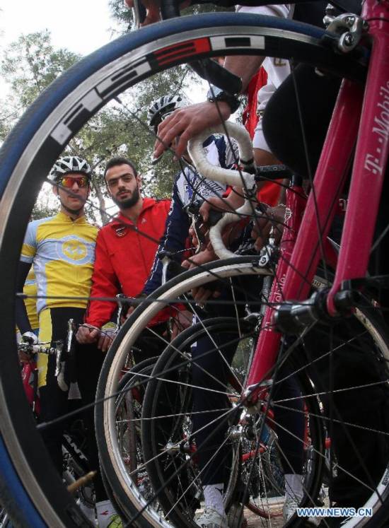 Locals ride bicycles on a street in Damascus, Syria, Nov. 21, 2014, as part of a campaign aimed to raise awareness among Syrians on energy-saving and environmental protection. 