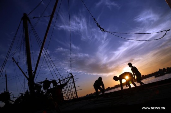 Laborers work on a cargo ship on the bank of Yangon river in Yangon, Myanmar, Dec. 1, 2014. 