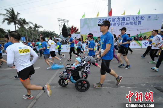 海口马拉松赛有近万人参赛,图为一位父亲推着婴儿车跑步。 骆云飞 摄