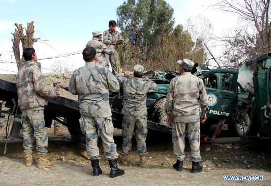 Afghan policemen gather around a destroyed police vehicle following a blast in Jalalabad city, capital of Nangarhar province, Afghanistan, Jan. 24, 2015. 