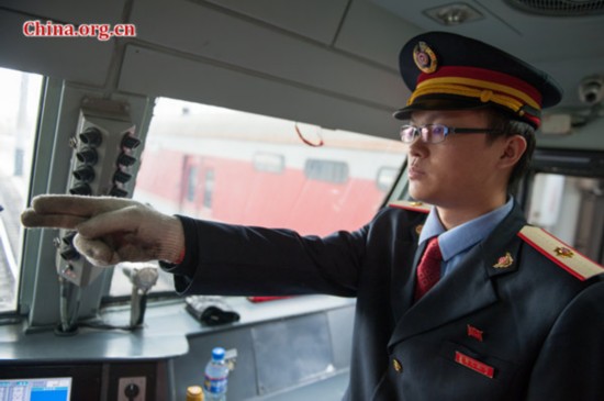 Song points two fingers at a railway signal, in a bid to ensure he is actually looking at the signal light. [Photo by Chen Boyuan / China.org.cn]