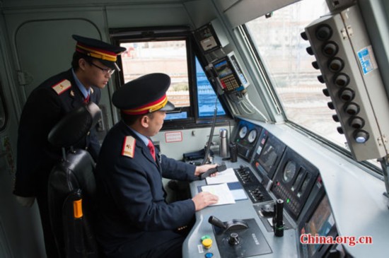 Song Jian (R) and his master, the locomotive's chief engineer jointly perform a visual confirmation of the meters before the train is set in motion. [Photo by Chen Boyuan / China.org.cn]