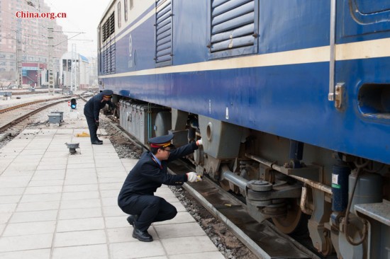 The locomotive's driver and chief engineer Ding Hailong (L) uses a spanner to tighten loose bolts while Song Jian, who is a deputy driver, is only authorized to perform the visual inspection. [Photo by Chen Boyuan / China.org.cn]