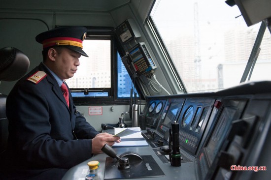 The locomotive's chief engineer and driver Ding Hailong reads the daily memo once again before setting the locomotive in motion. [Photo by Chen Boyuan / China.org.cn]